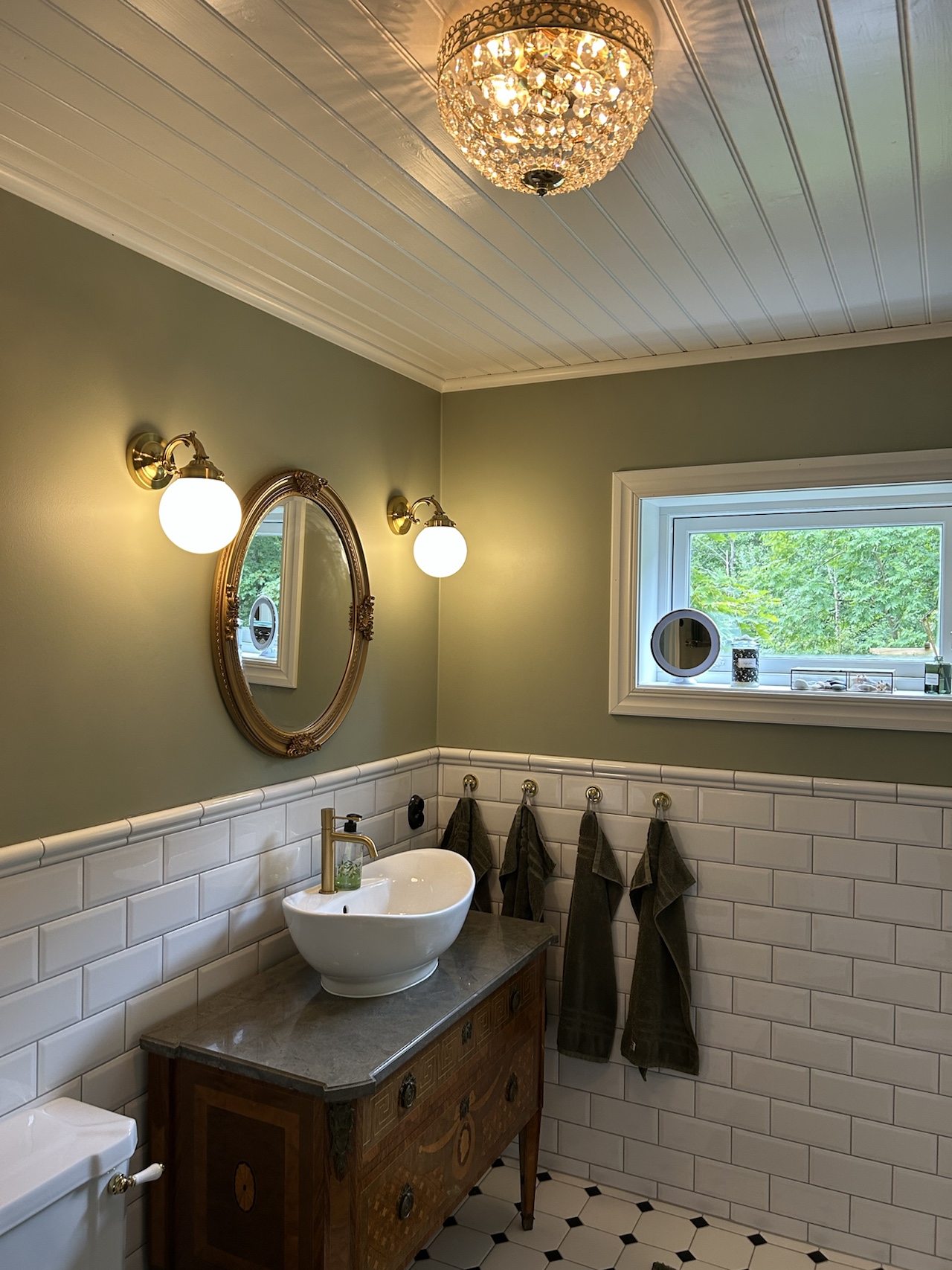 Bathroom vanity with a round mirror, twin wall lights and a window