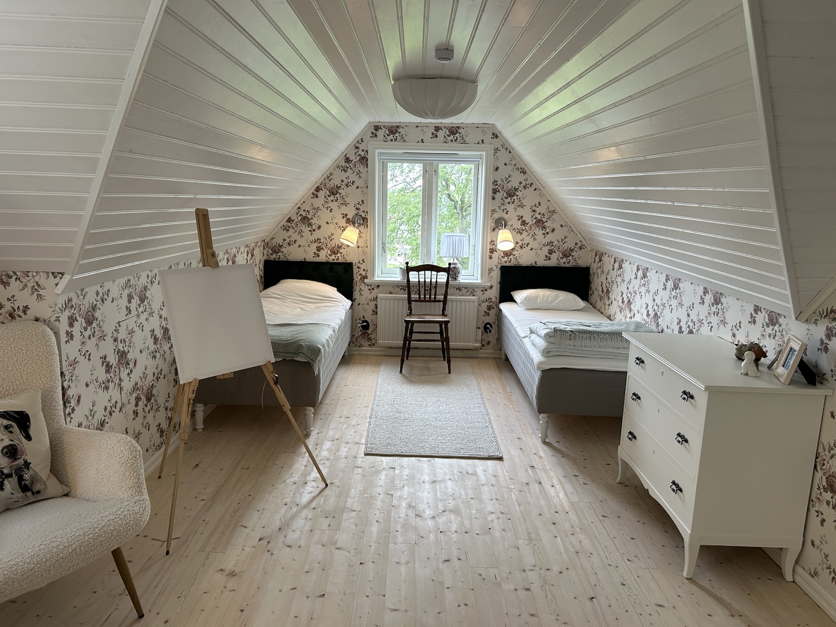 Airy attic bedroom with two single beds beneath a white sloping ceiling