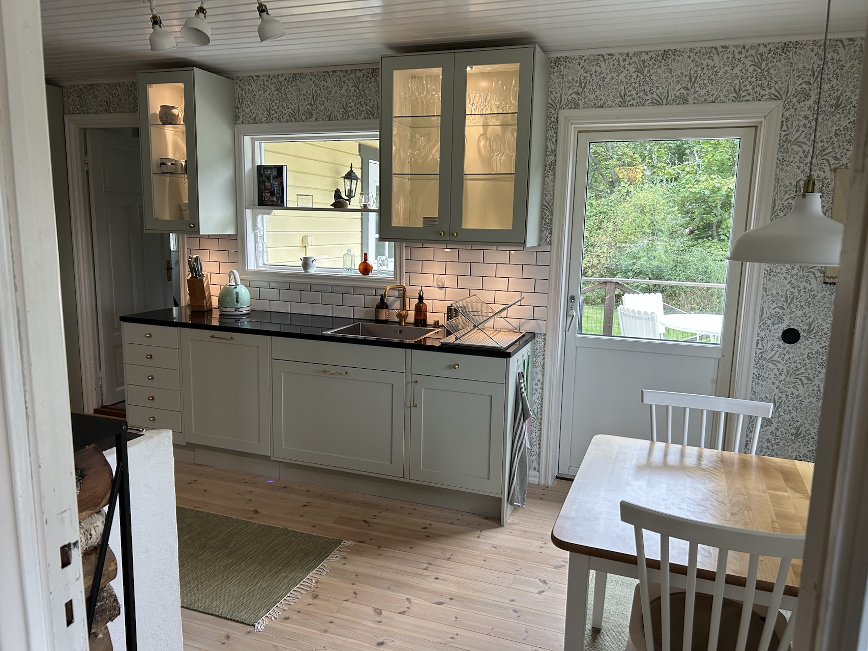 Kitchen dining area with light green cabinetry, garden-facing windows and access to the wooden deck