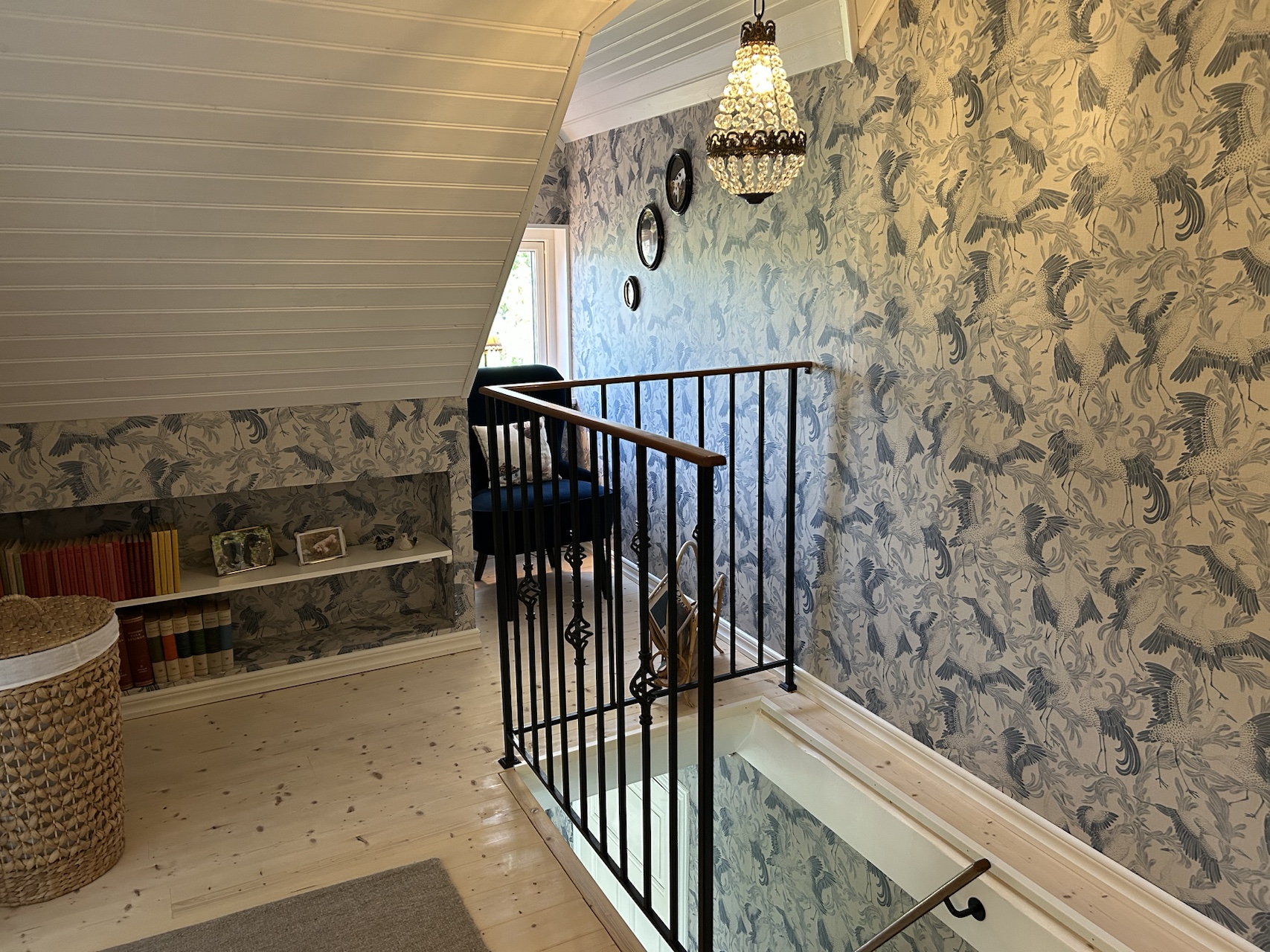 Upstairs landing with patterned wallpaper and a dark wooden stair railing